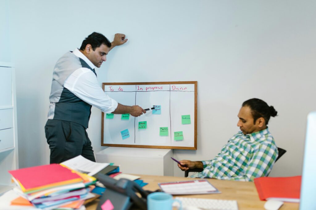 Two men collaborating on a project using a whiteboard in an office setting.